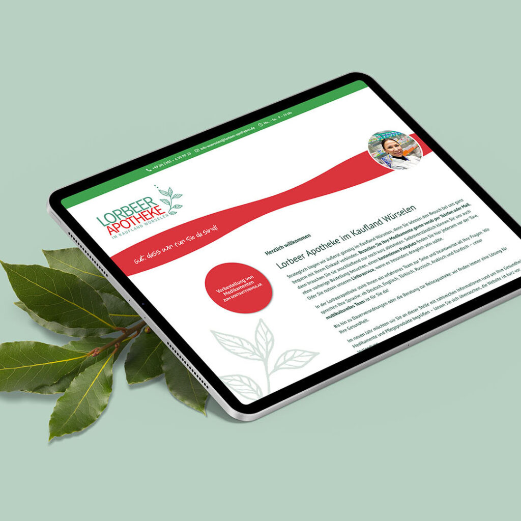 Foto von einem Tablet mit der Website "Lorbeer Apotheke" auf grünem Untergrund neben Lorbeerblättern.